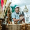 smiling man holds the clipboard while list items among craft items in the craft gallery